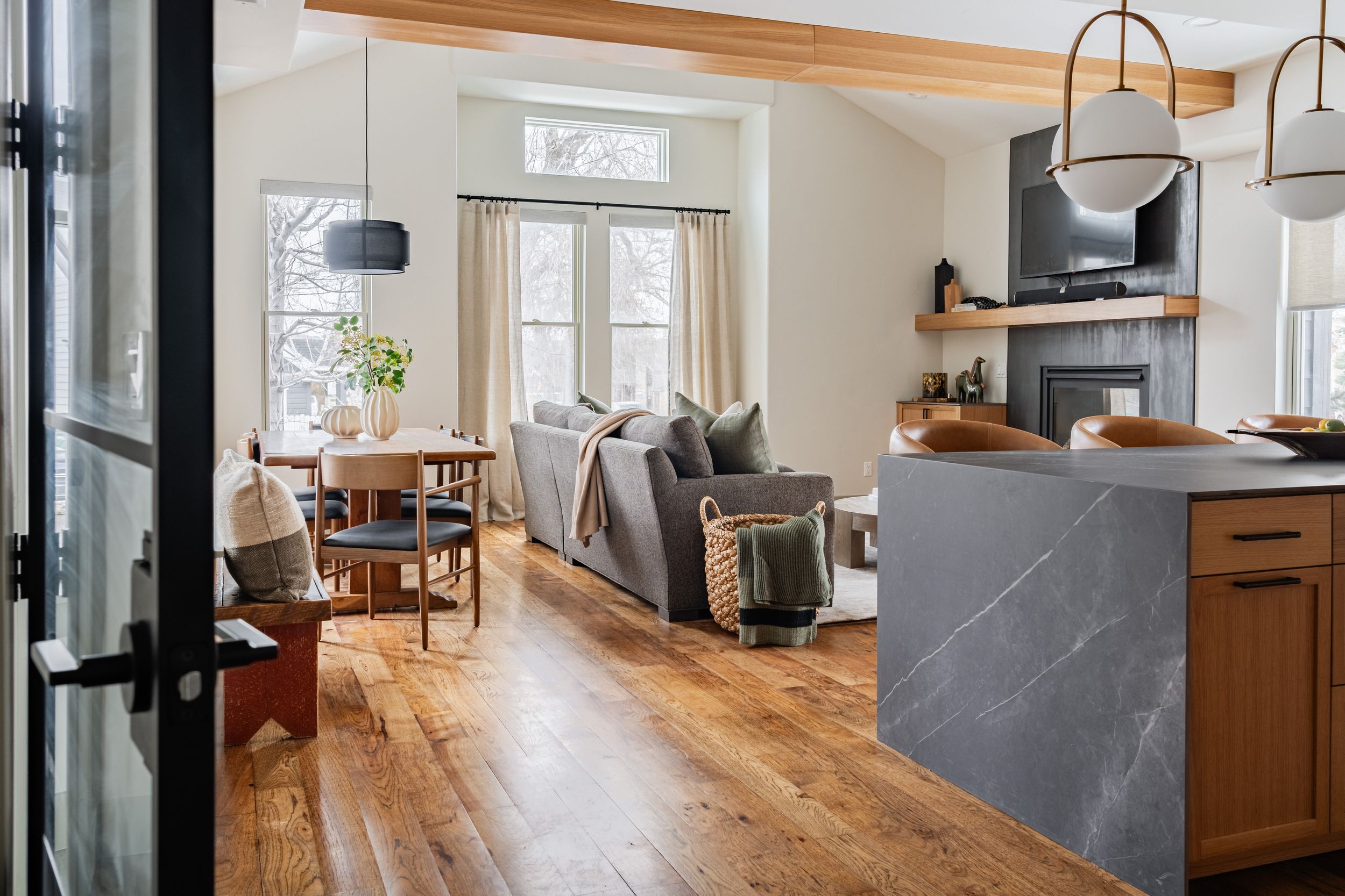 Modern living room with hardwood floors, black steel-framed windows, and custom built-in cabinets with wood accents.