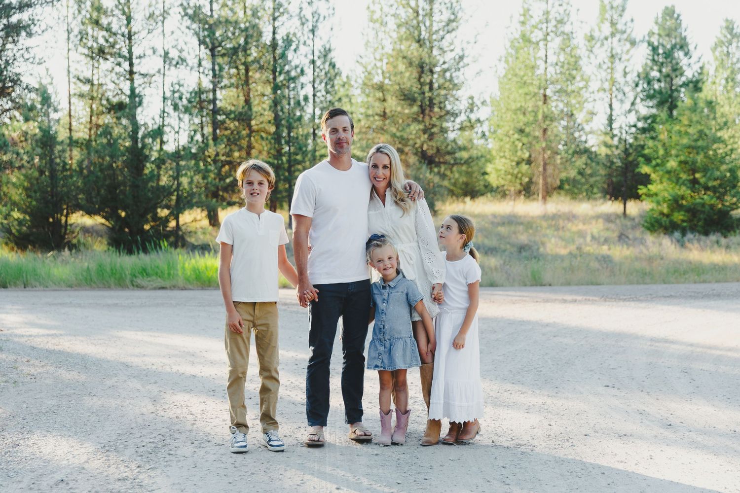 Family walking together through a scenic mountain meadow at sunset.