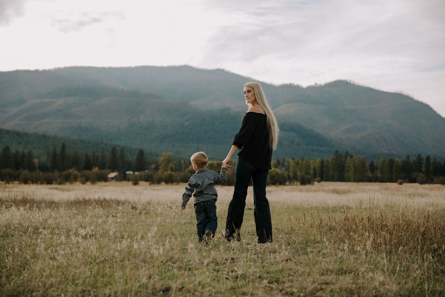 Family walking together through a scenic mountain meadow at sunset.