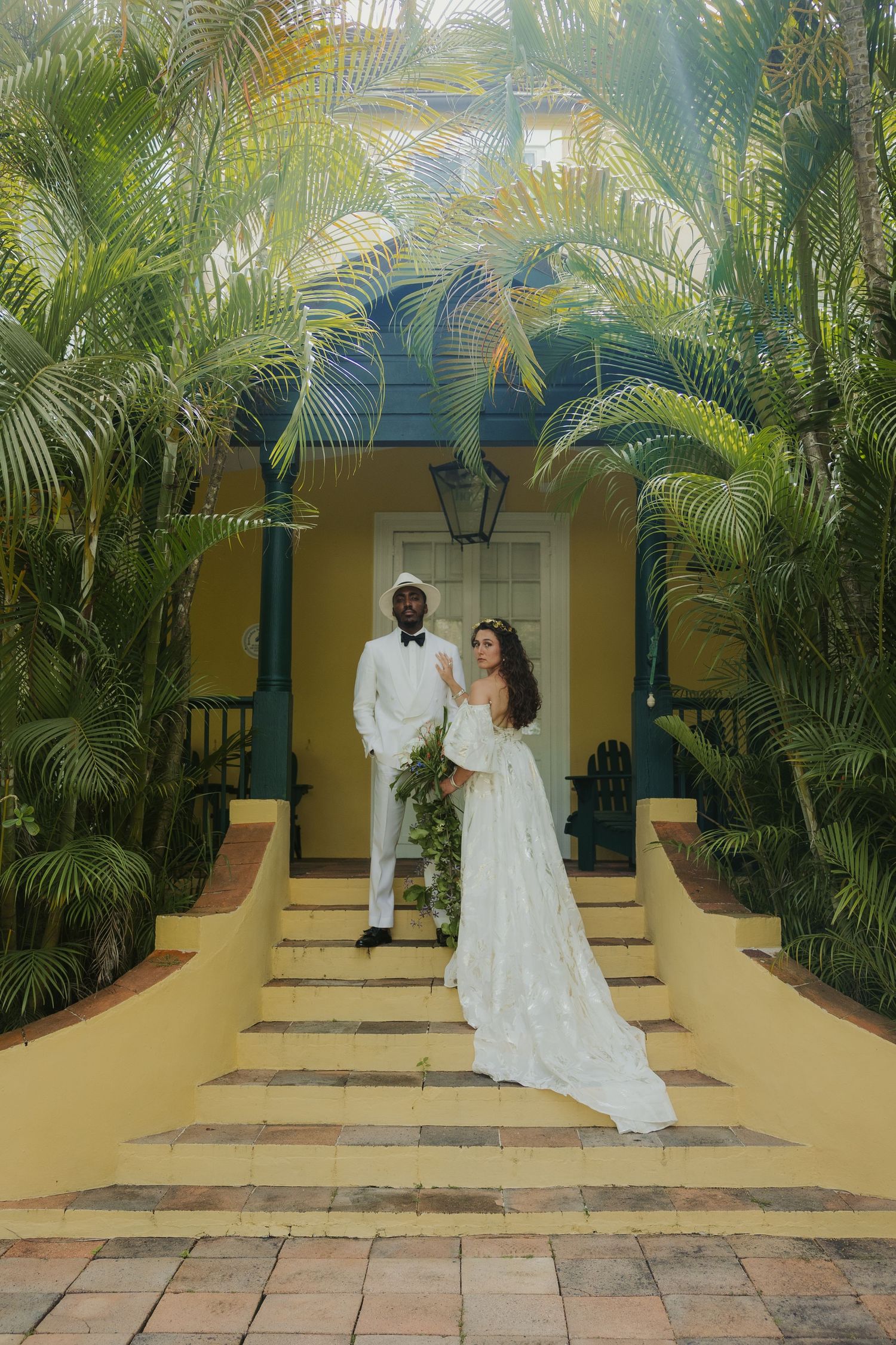 Tropical garden wedding setting in Barbados with palm trees and yellow building facade.
