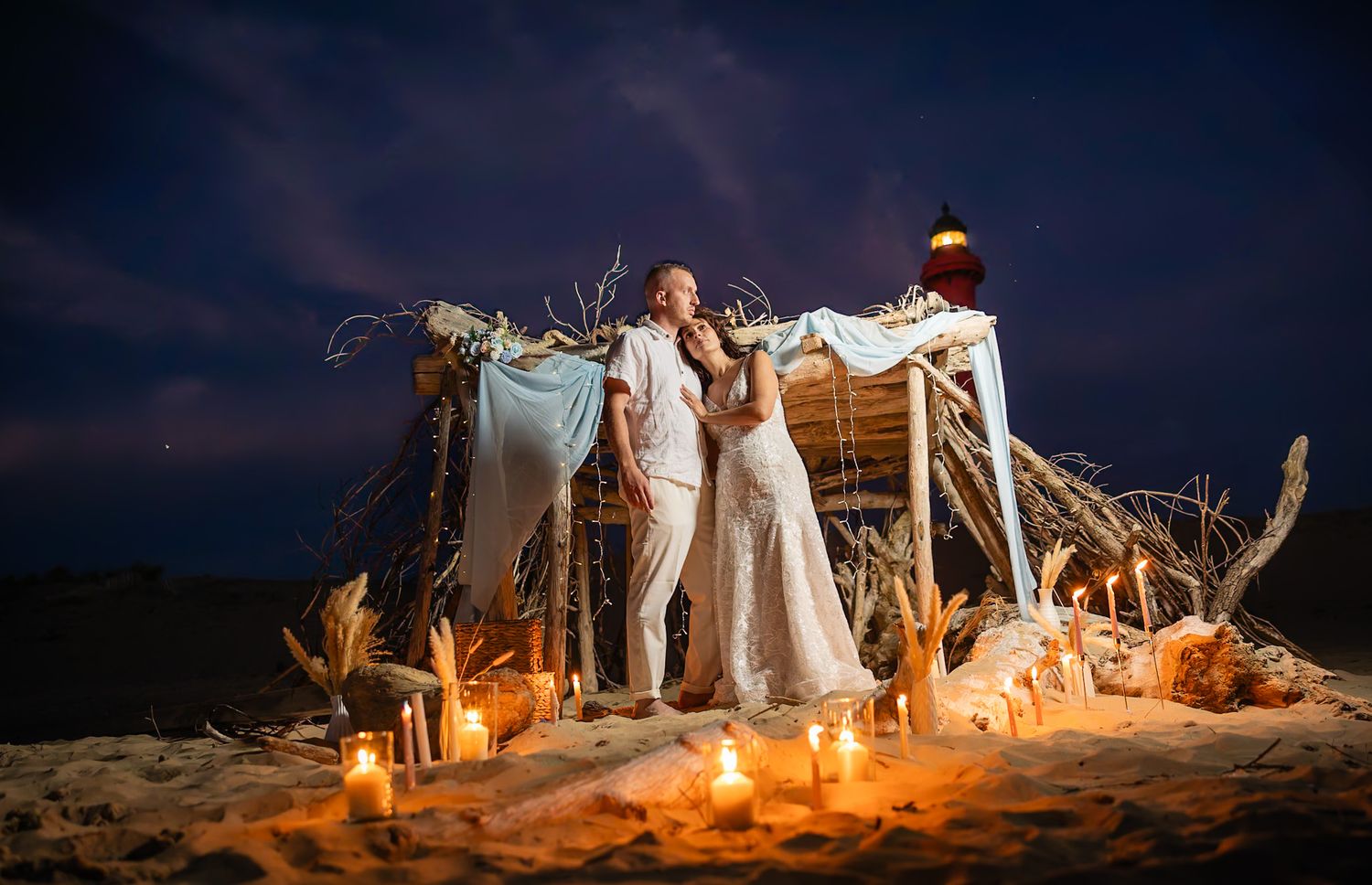 A couple embraces intimately in front of twinkling bokeh lights creating a romantic silhouette scene.