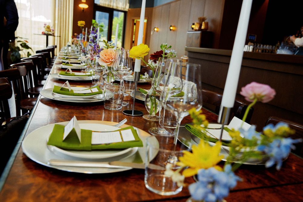 Formal dining table set with crystal glasses, white plates and colorful floral centerpieces.
