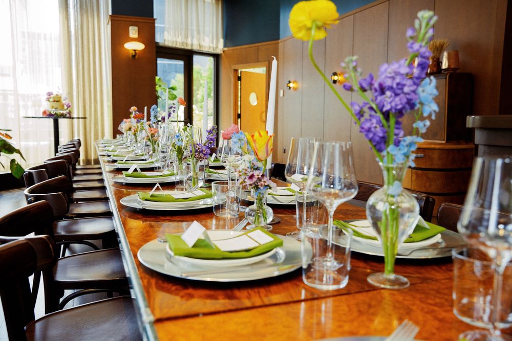 Elegant table setting with white plates, wine glasses and purple floral centerpieces in an upscale restaurant interior.