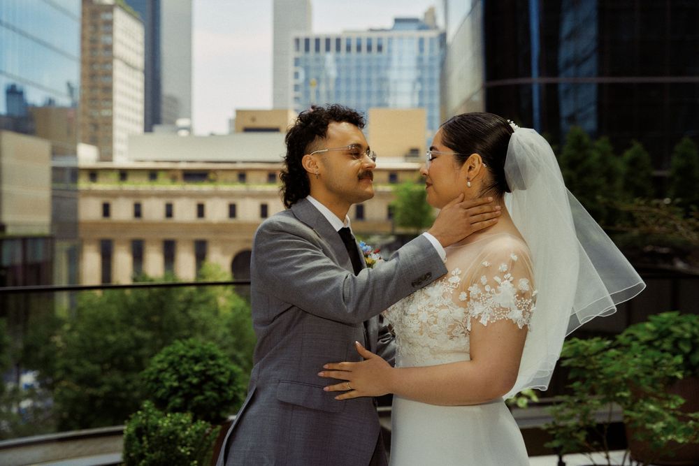 A tender moment between newlyweds with city buildings in the background.