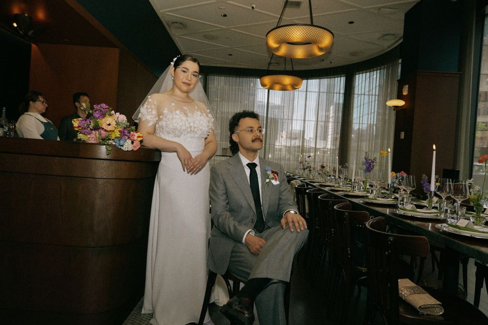 An intimate wedding reception setup in a modern restaurant with city views.