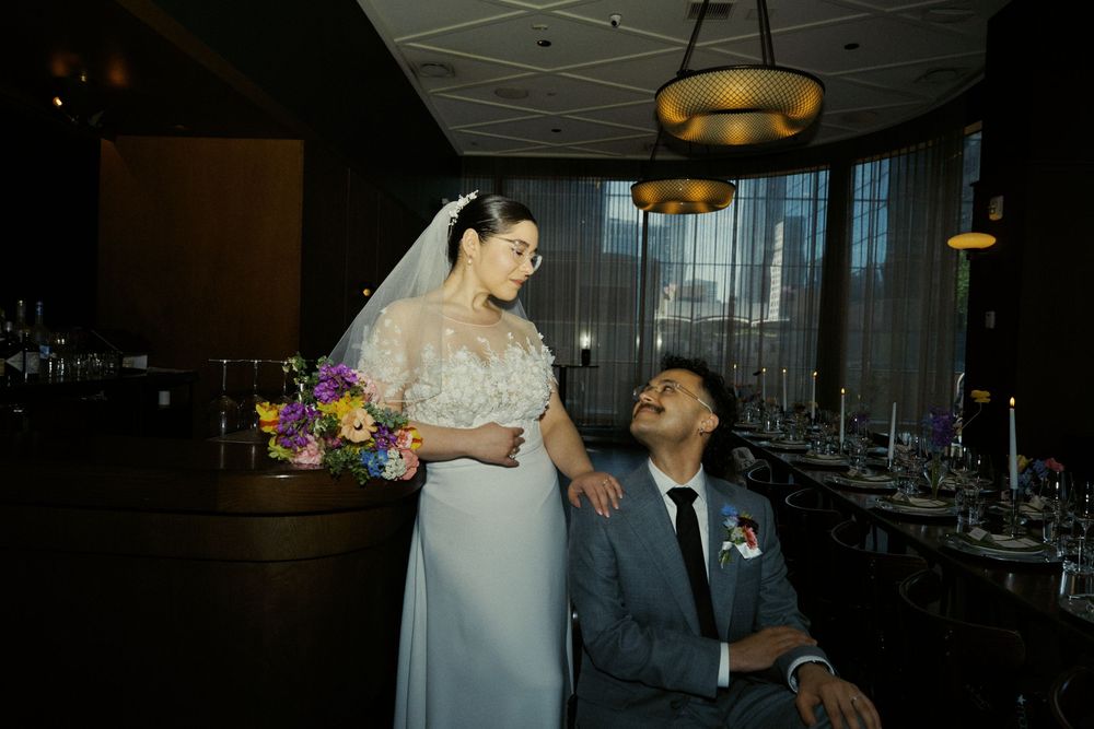 A couple poses for wedding photos in a modern restaurant setting with dramatic lighting.