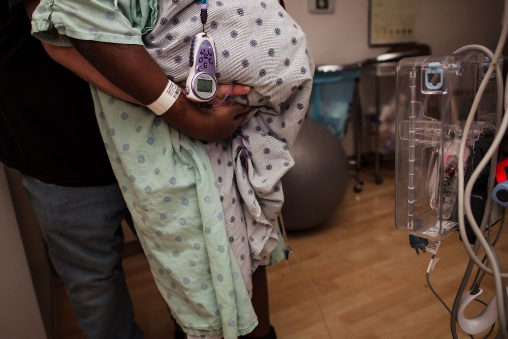 Healthcare providers assisting a patient in a hospital room with medical equipment.