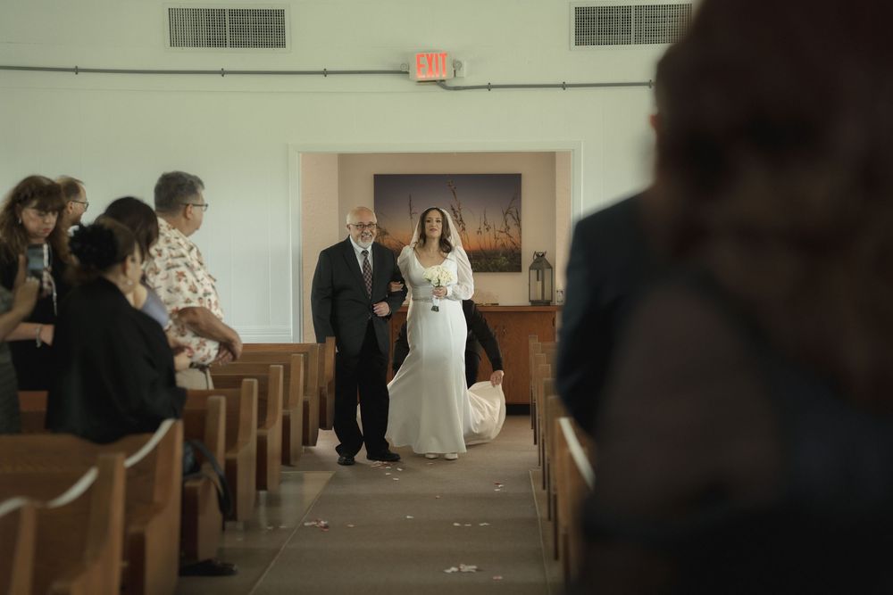 Interior view of a church aisle with wooden pews and white walls during a ceremony.
