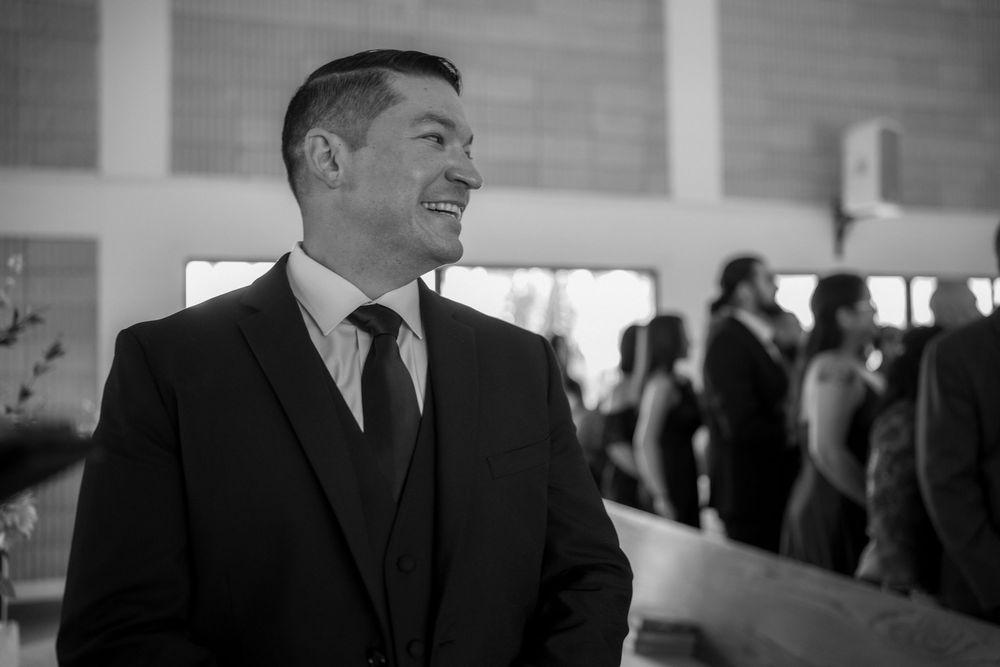 A black and white photo of a well-dressed man in a suit smiling at an event.