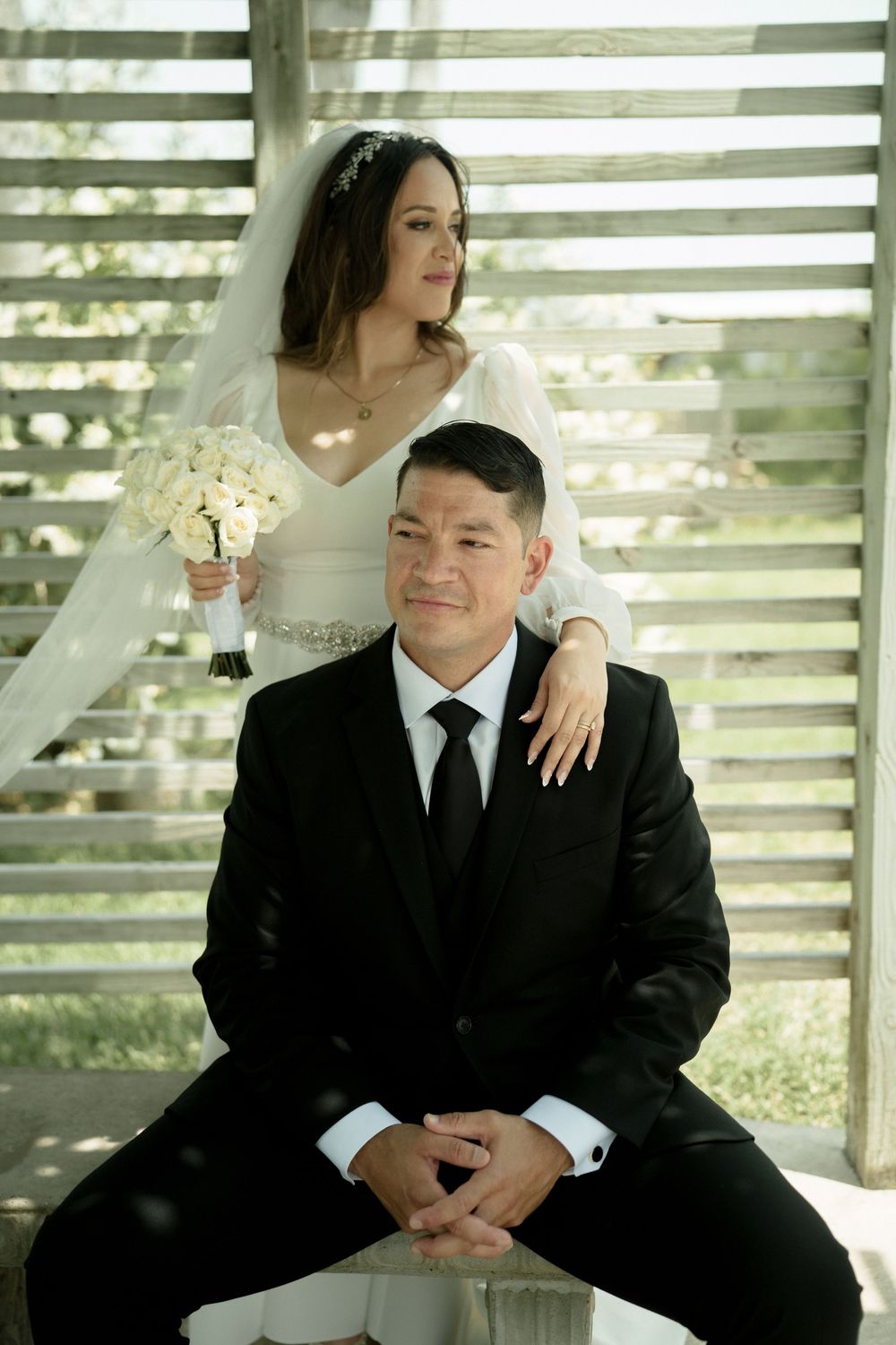 A couple poses in dappled sunlight during their wedding photoshoot.
