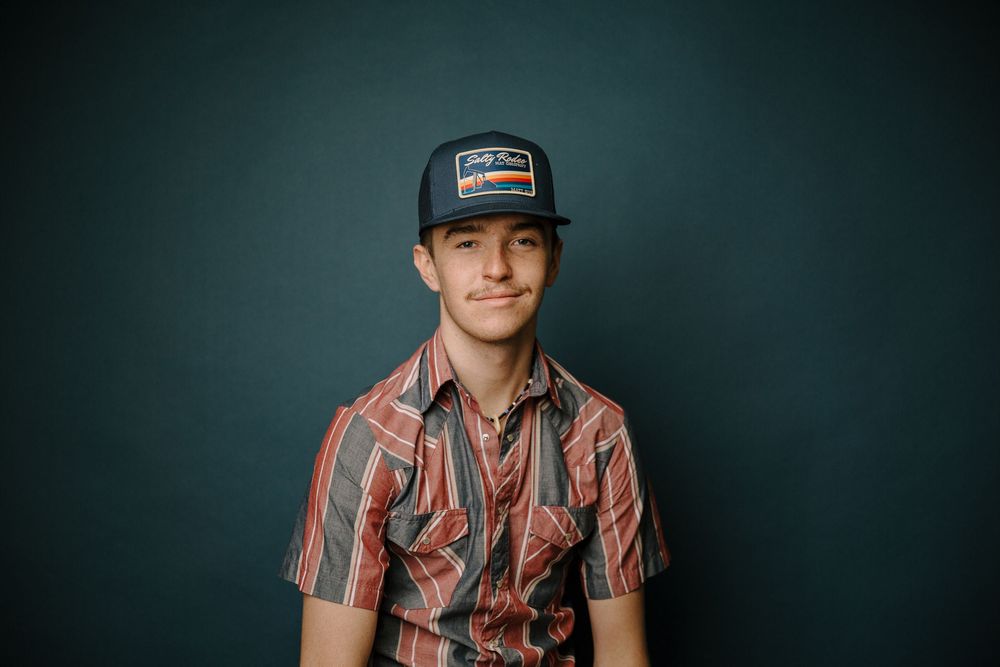 Portrait series against dark background showing person wearing striped shirt and baseball cap.