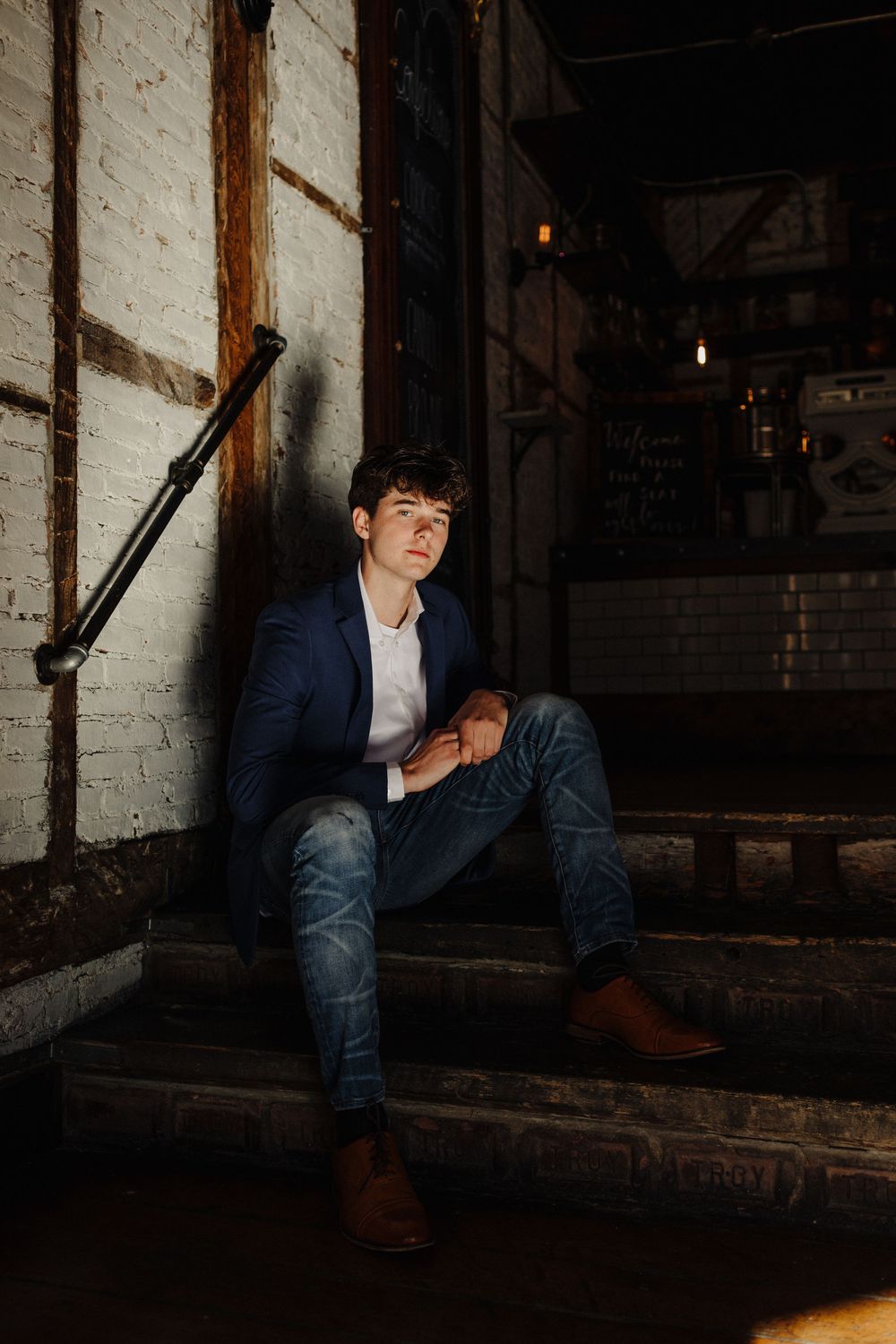 Dramatic portrait in dark industrial setting with person wearing navy suit.