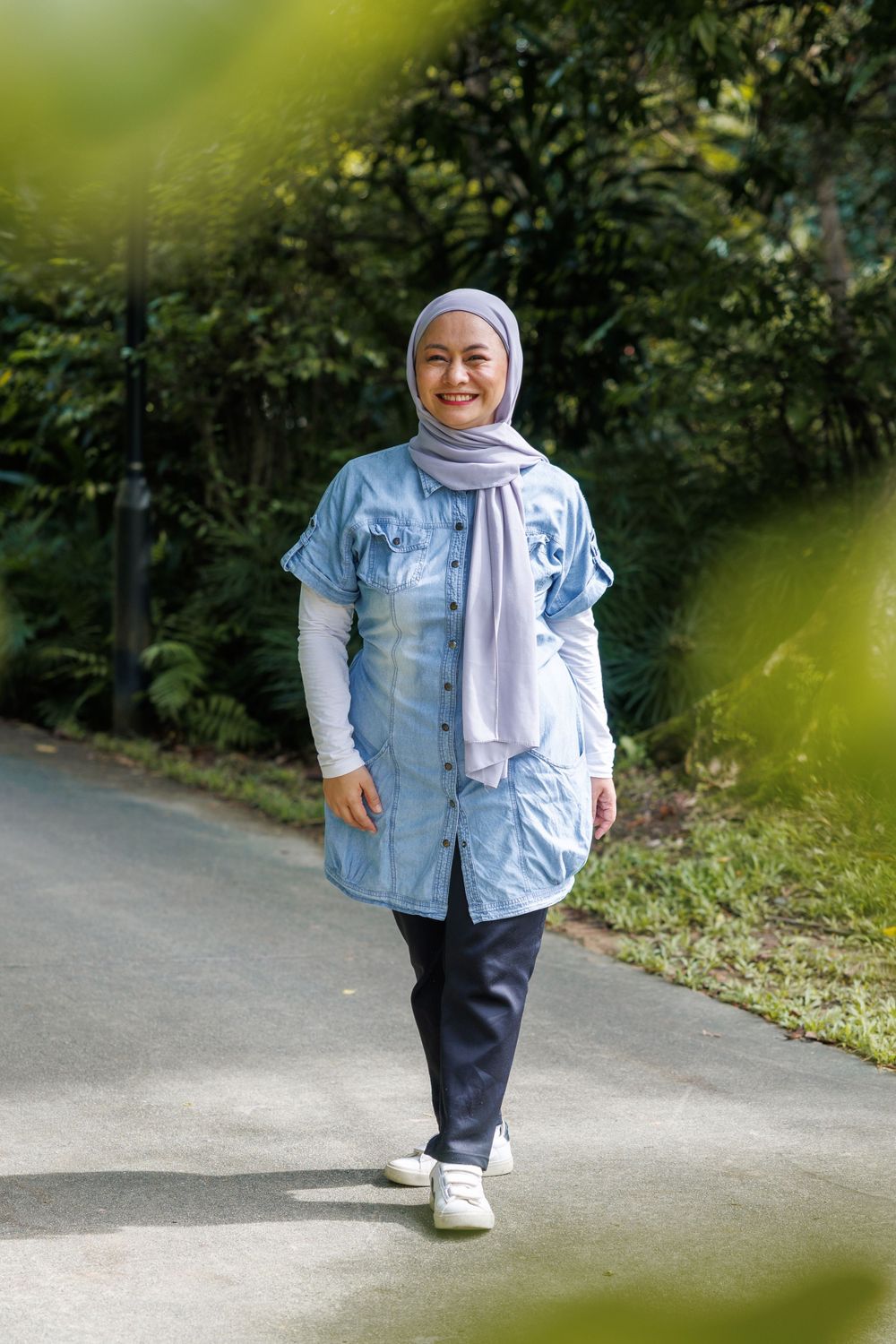 Casual denim and hijab street style captured on garden pathway.