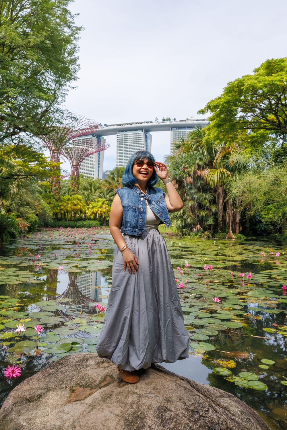Grey tulle skirt and denim vest outfit photographed by lotus pond with Marina Bay Sands backdrop.