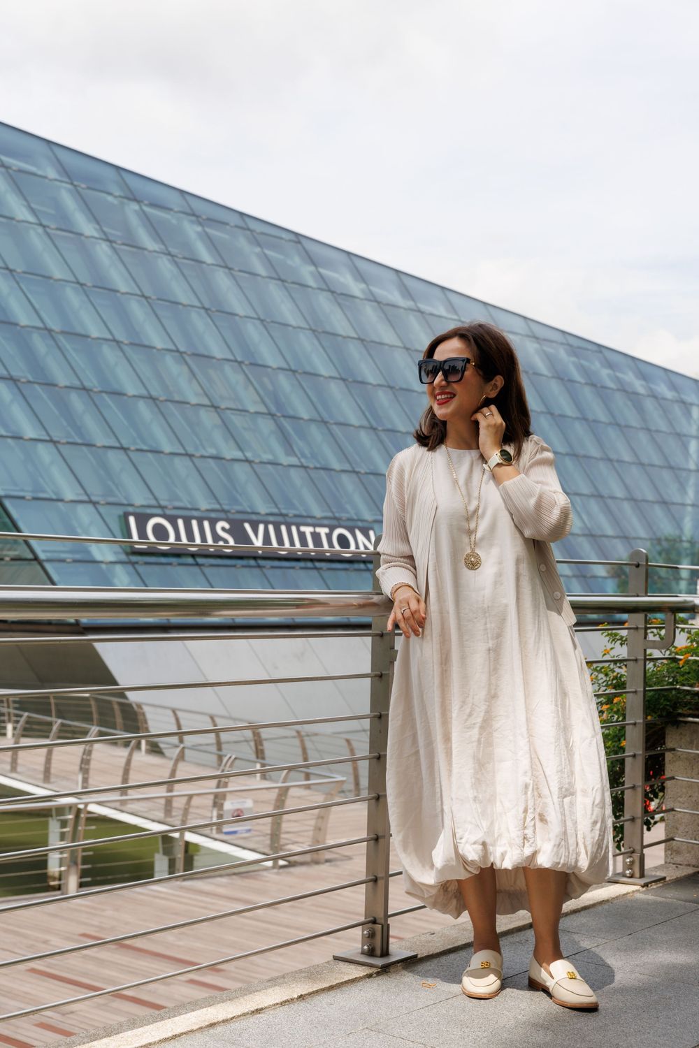 Fashionable white dress ensemble photographed at the Louis Vuitton storefront with modern architecture.