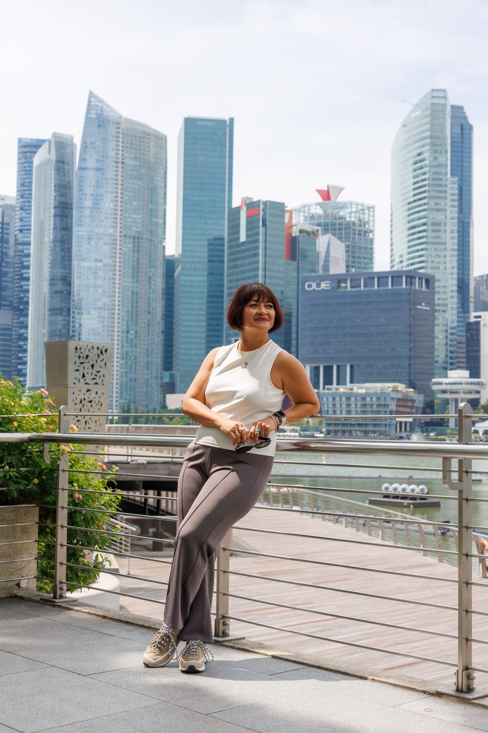 Athletic woman in casual wear poses confidently against Singapore's downtown skyline.