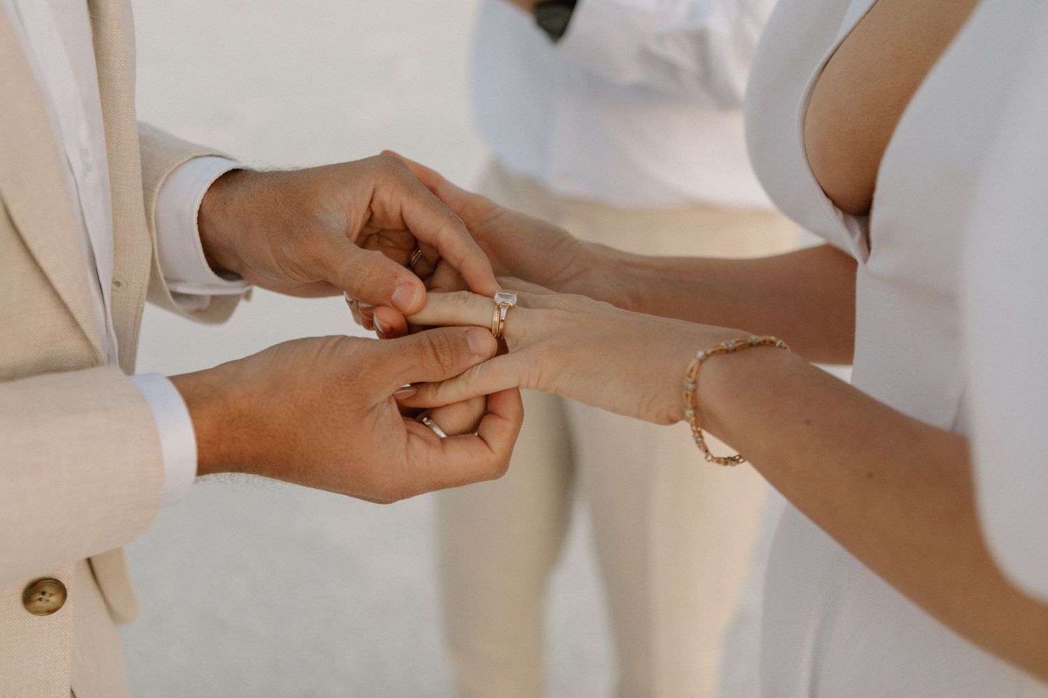Close-up view of hands exchanging wedding rings during an intimate ceremony.
