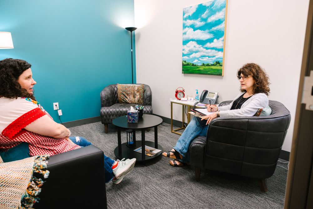 Two people having a counseling or therapy session in a modern office with blue walls.