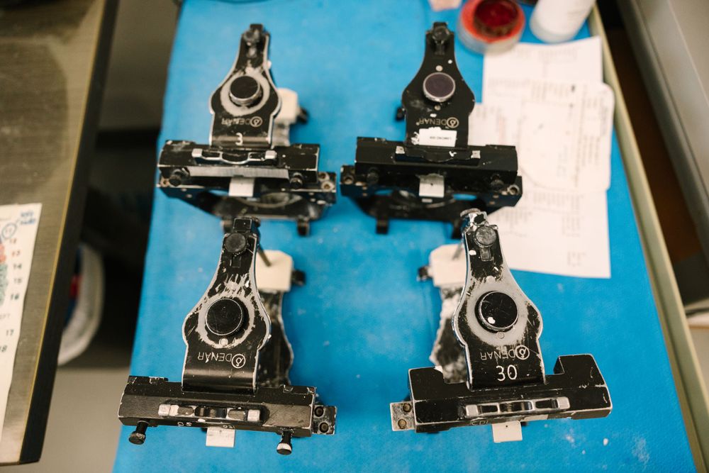 Four black mechanical components laid out for inspection on a blue surface.
