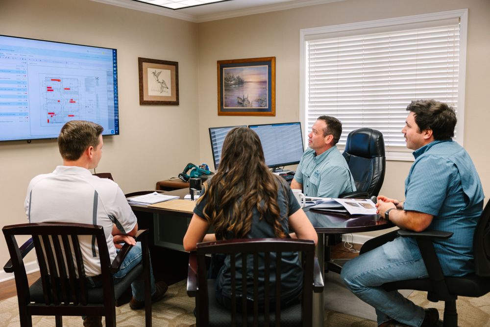 Team meeting in office with digital display showing workflow diagram.