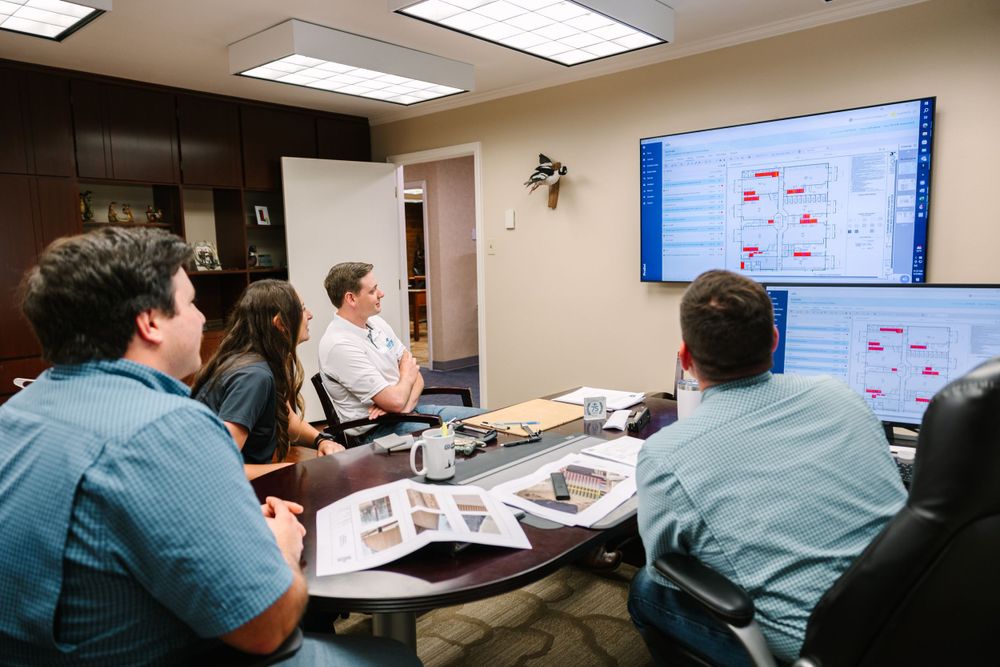 Business team reviewing presentation on wall-mounted screen in conference room.