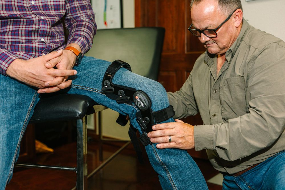 Medical professional adjusting a knee brace or orthopedic device during patient consultation.