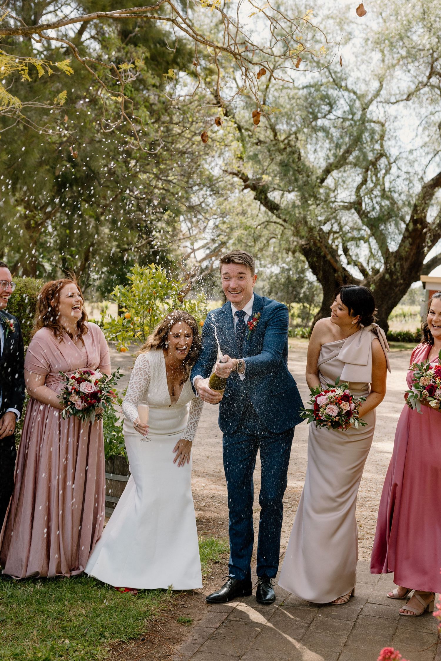 Wedding party celebrating with confetti in garden setting. Captured by G Dovaston Photography