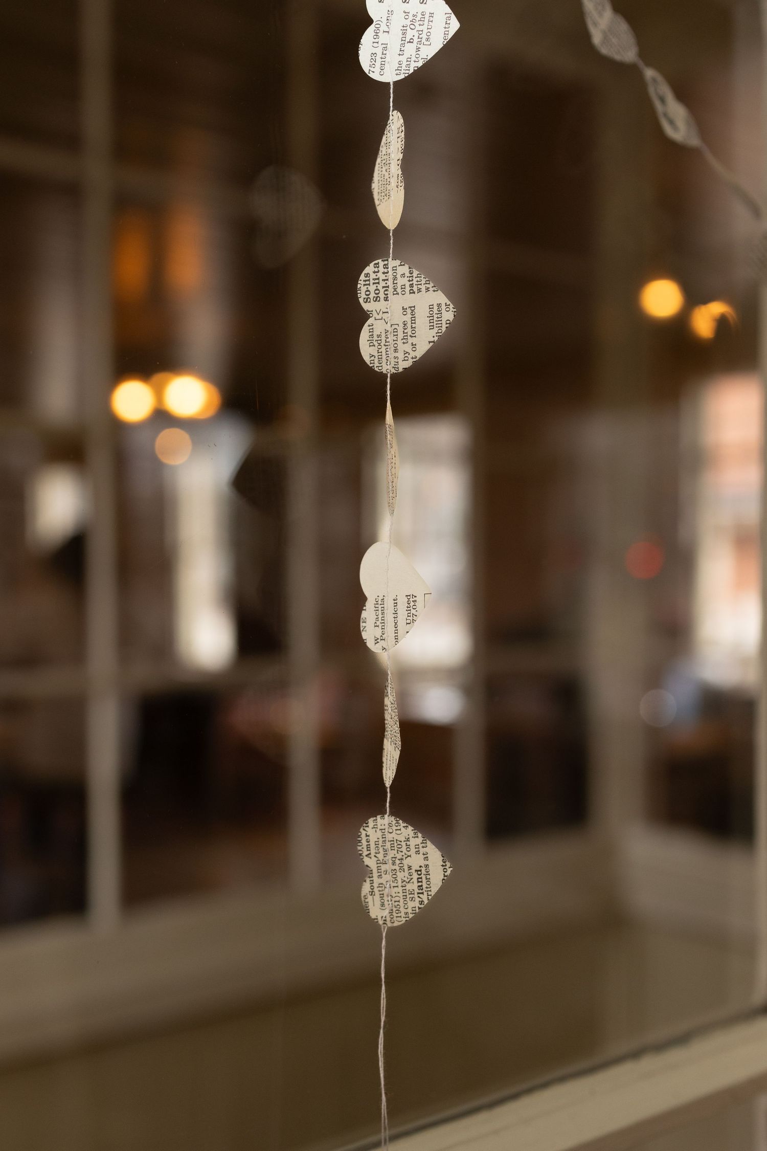 Decorative paper heart garlands hanging against a blurred bokeh background.