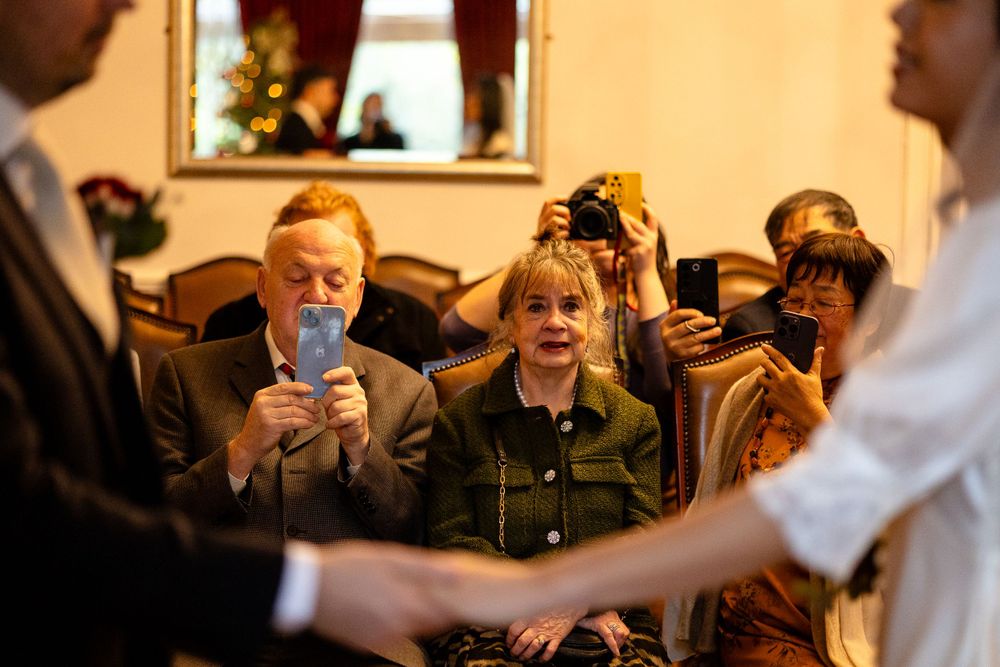 Wedding guests watching the ceremony in an indoor venue with ornate decor.