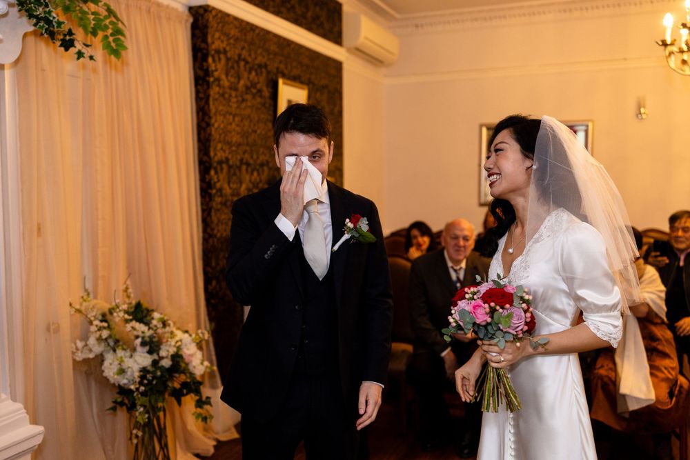 An emotional ceremony moment in an elegant indoor venue with floral decorations.