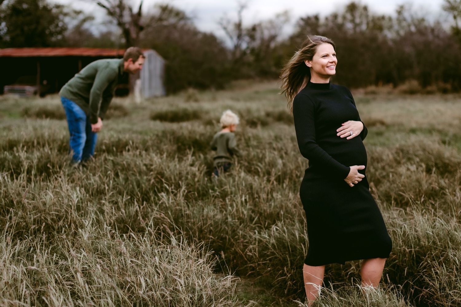 Two people enjoying moments outdoors in a natural field with tall grass on an overcast day.