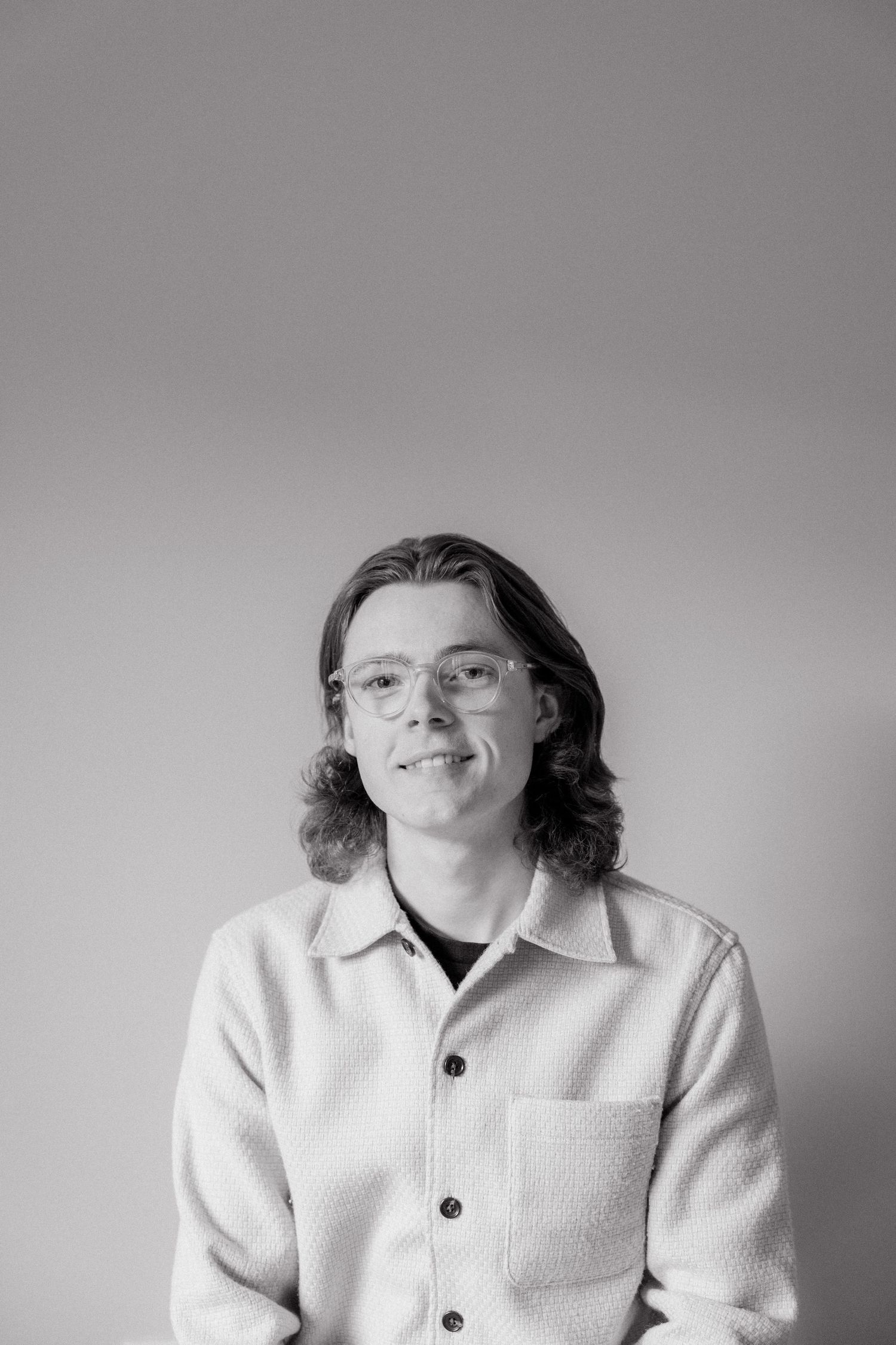 Black and white portrait photo of someone wearing glasses and a light-colored button-up cardigan.