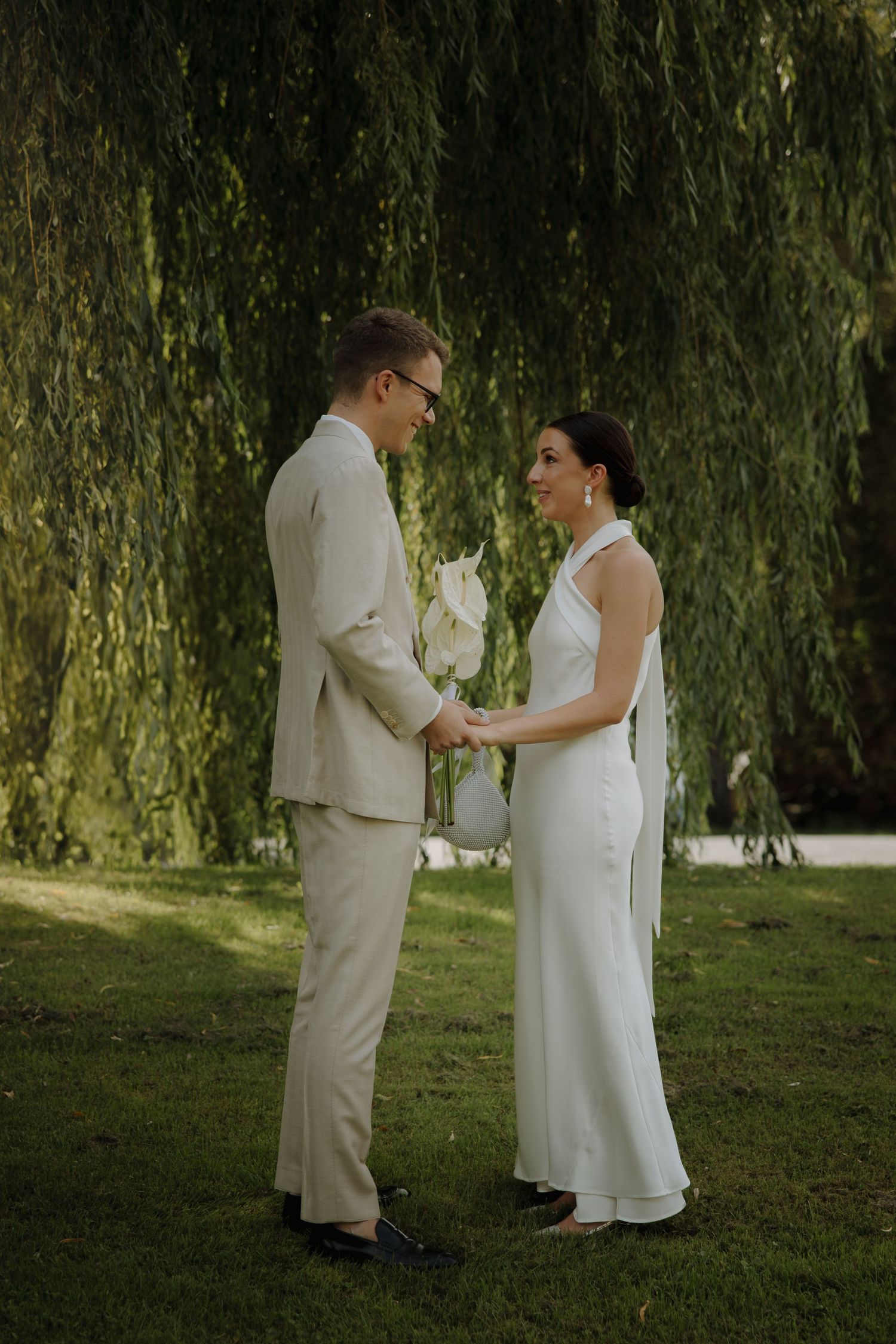 Couple sharing a romantic moment under a weeping willow tree in natural lighting.