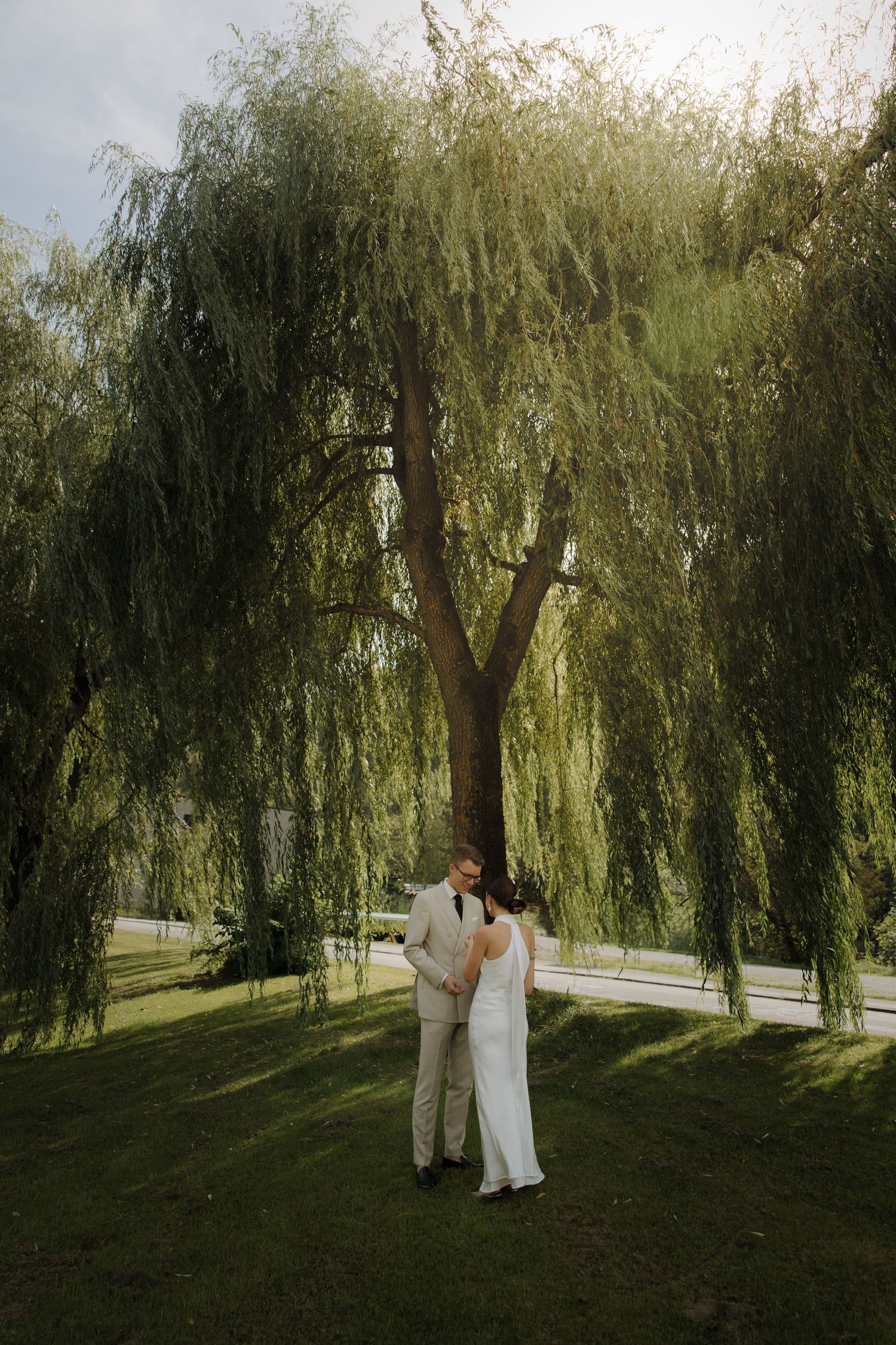 Couple embracing under a majestic weeping willow tree in a garden setting.