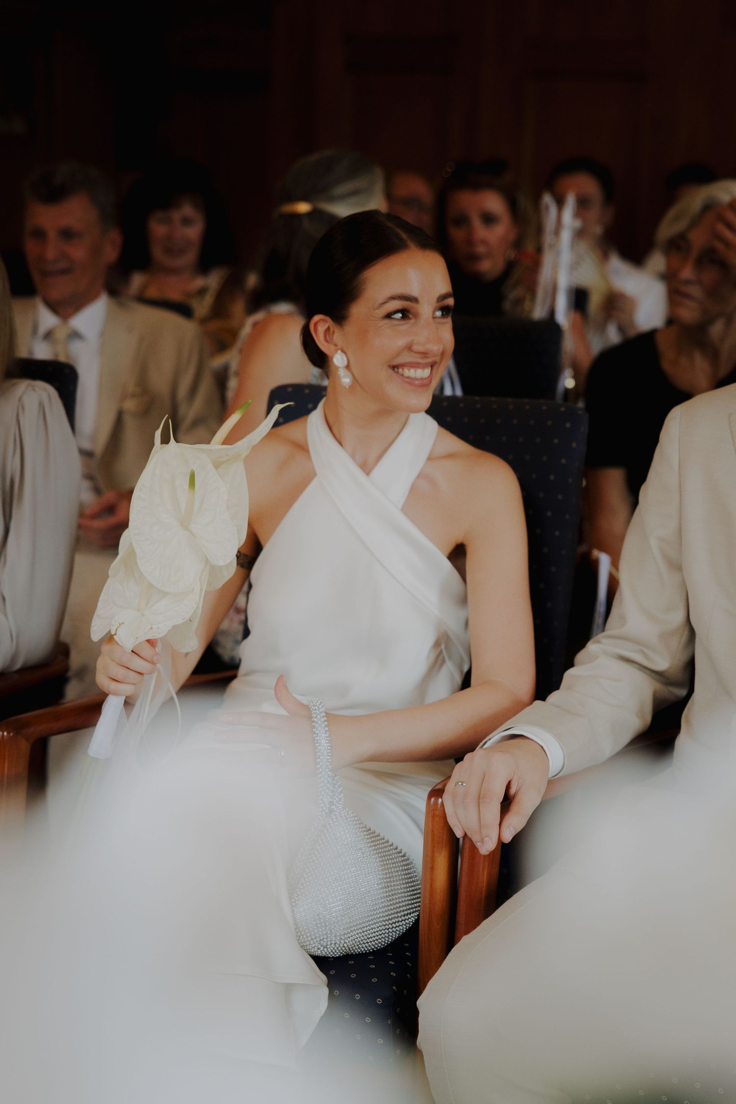 Wedding party members in white formal attire seated together during a reception celebration.