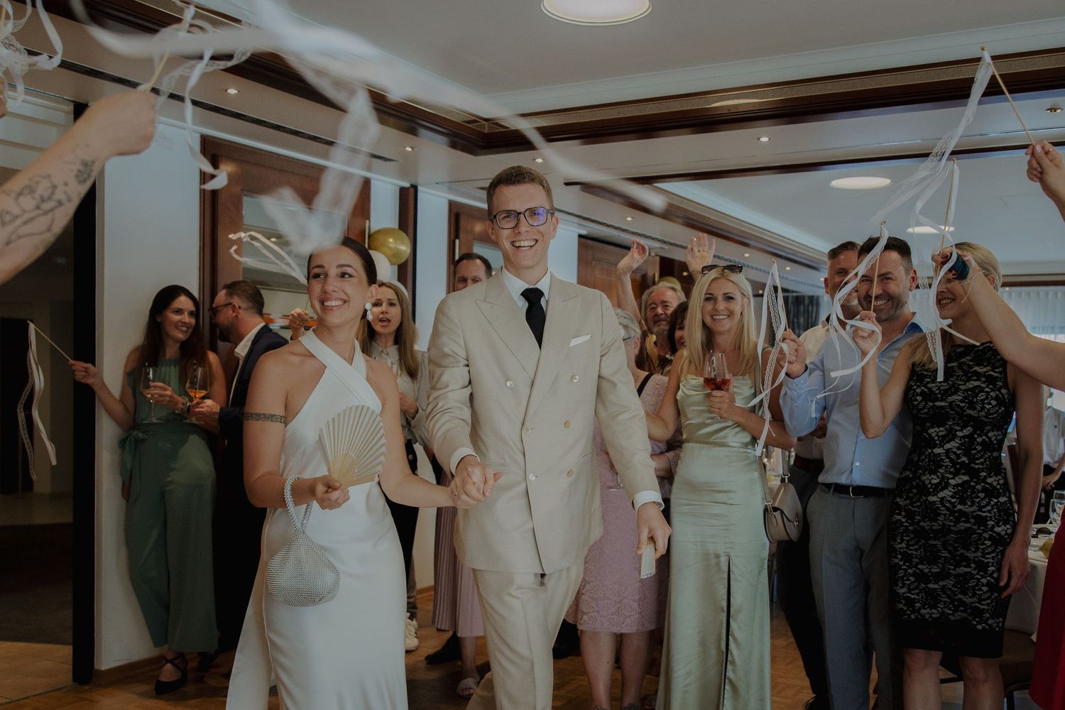 Wedding celebration with guests cheering in an indoor venue with festive decorations.