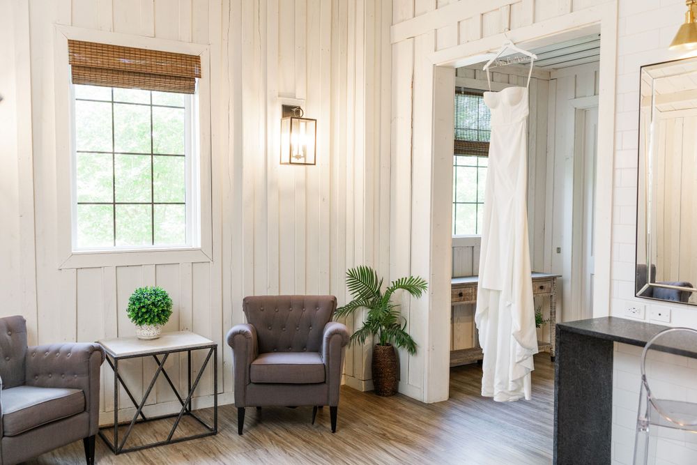 A cozy sitting area with grey armchair, decorative window and white shiplap walls.