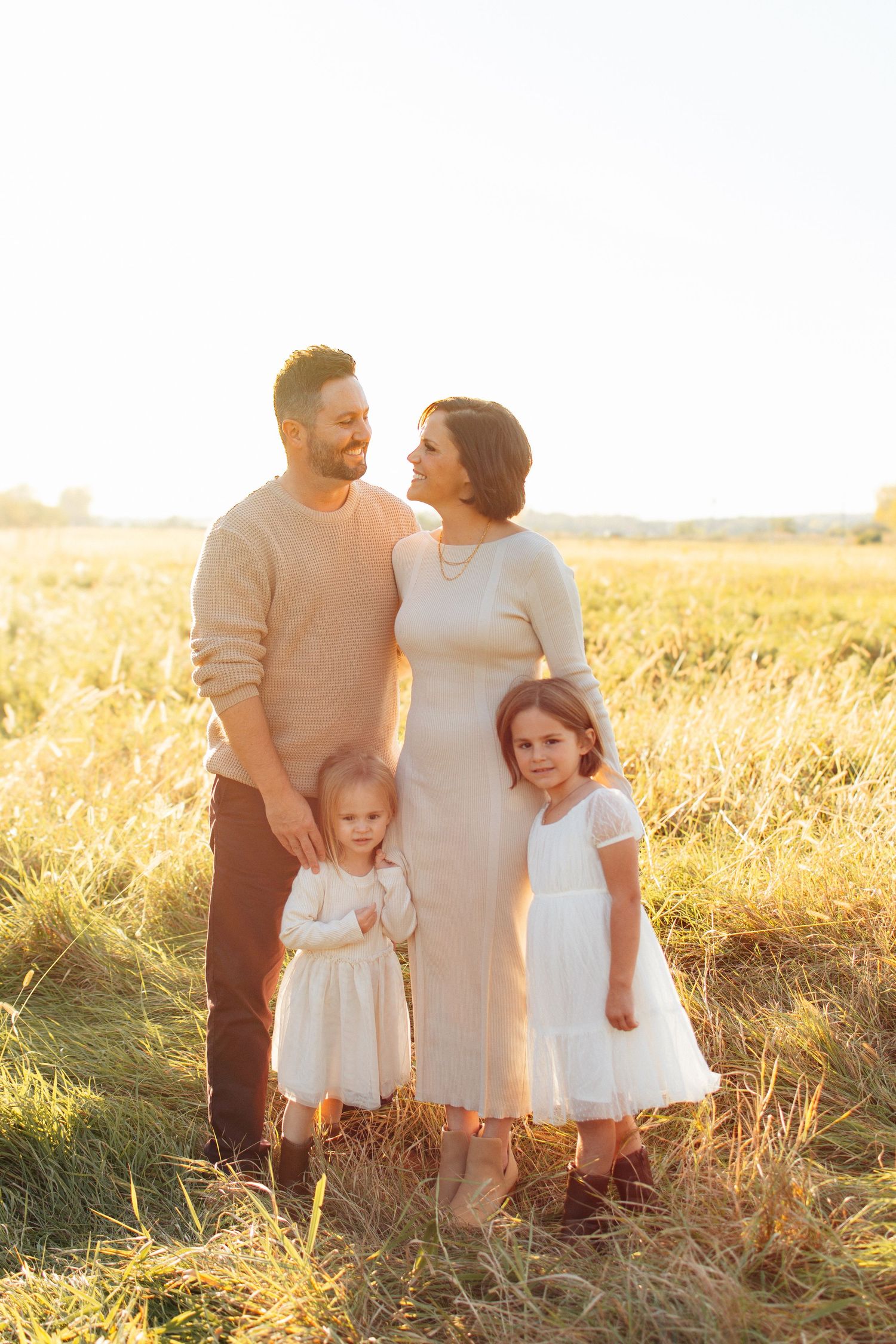 Family portrait in a golden wheat field at sunset.