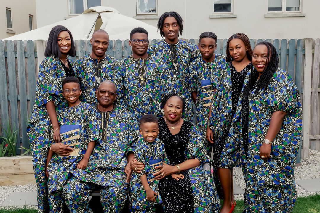 Group wearing matching blue floral print outfits poses together outdoors against a fence.