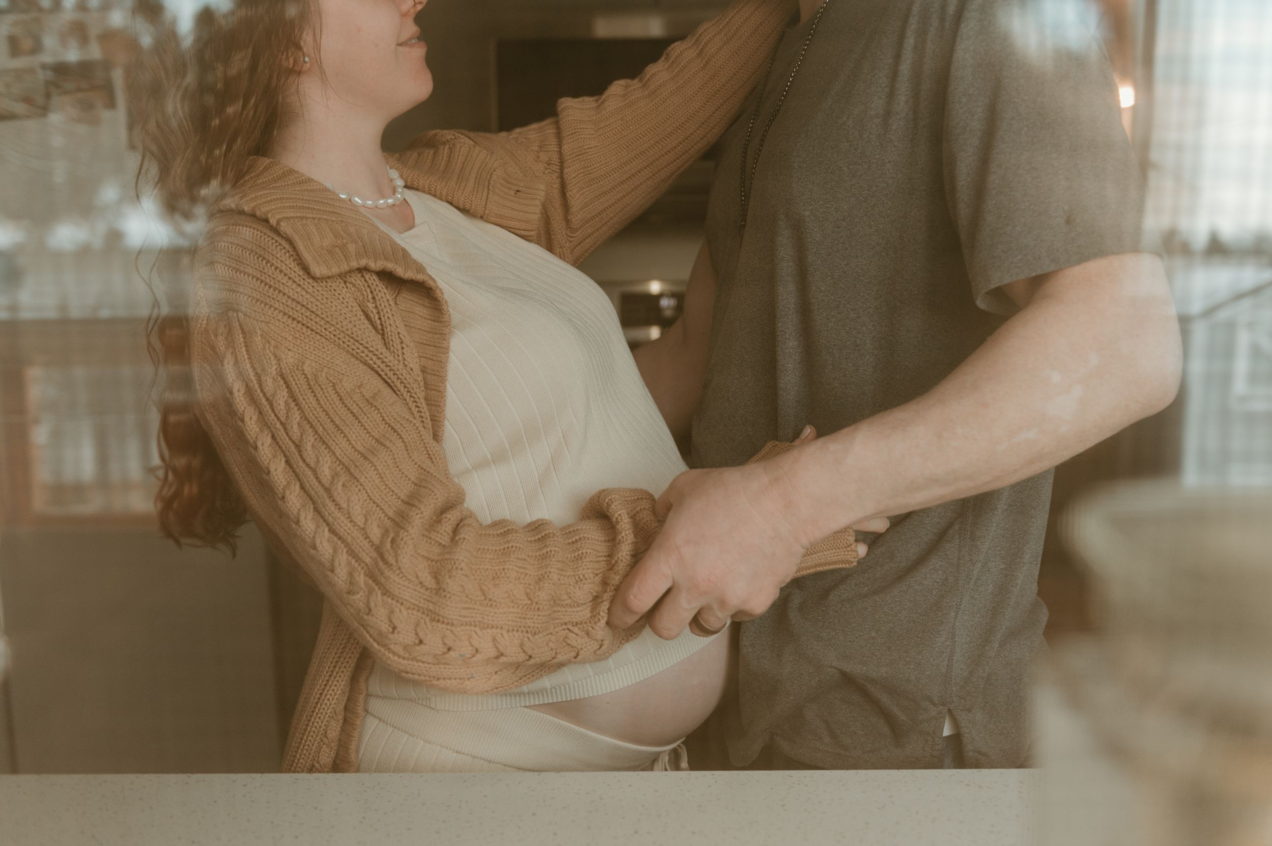 Couple in casual attire dancing together intimately in a room with soft, vintage-style lighting.