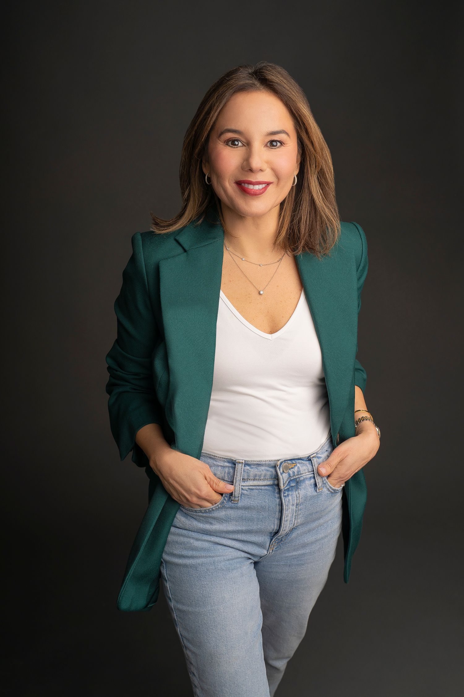 Professional headshot portrait with black sleeveless top against turquoise background.