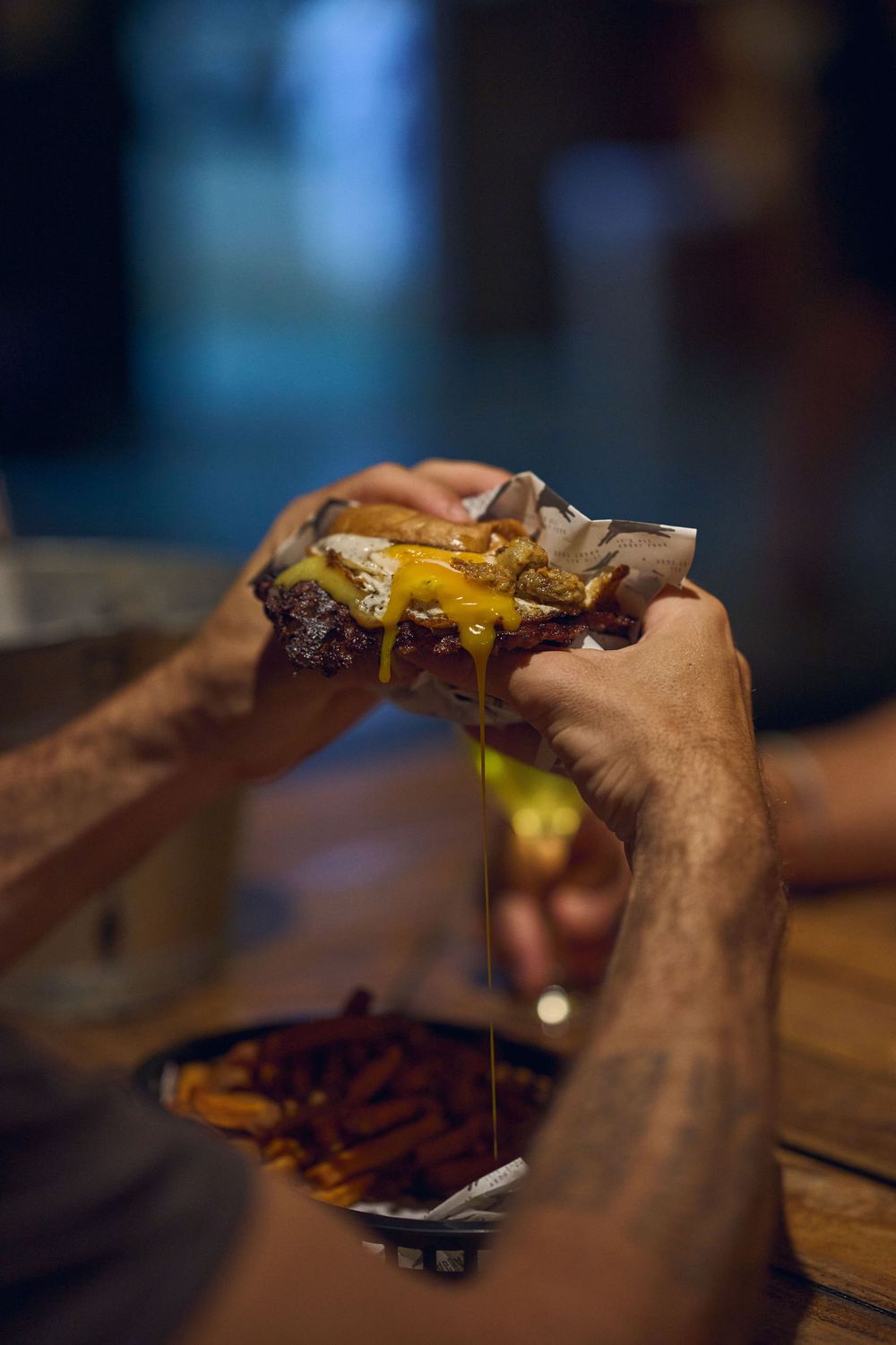 A series of sequential shots showing hands holding a dripping cheeseburger with melted cheese.