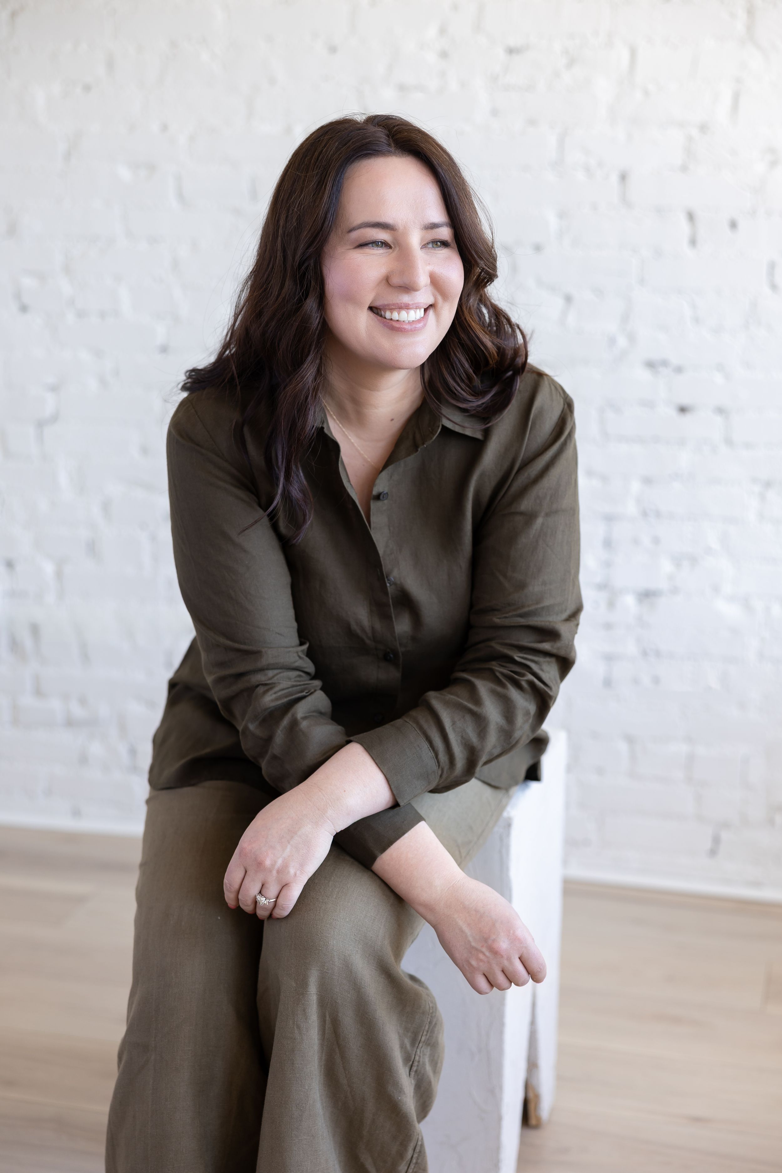 Woman business owner Talks Over Tea Mental Health Therapist in Tacoma, WA personal branding  sitting on white cube in studio looking out