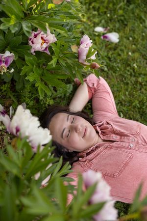Woman business owner Talks Over Tea Mental Health Therapist in Tacoma, WA personal branding  laying on grass near flowers in pink jumpsuit