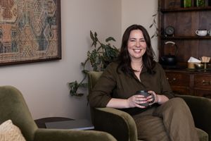 Woman business owner Talks Over Tea Mental Health Therapist in Tacoma, WA personal branding  siting in chair holding tea mug with tea behind