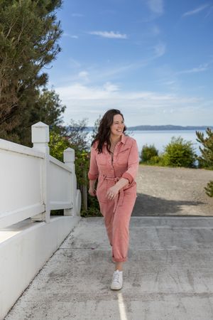 Woman business owner Talks Over Tea Mental Health Therapist in Tacoma, WA personal branding  walking through park in pink jumpsuit