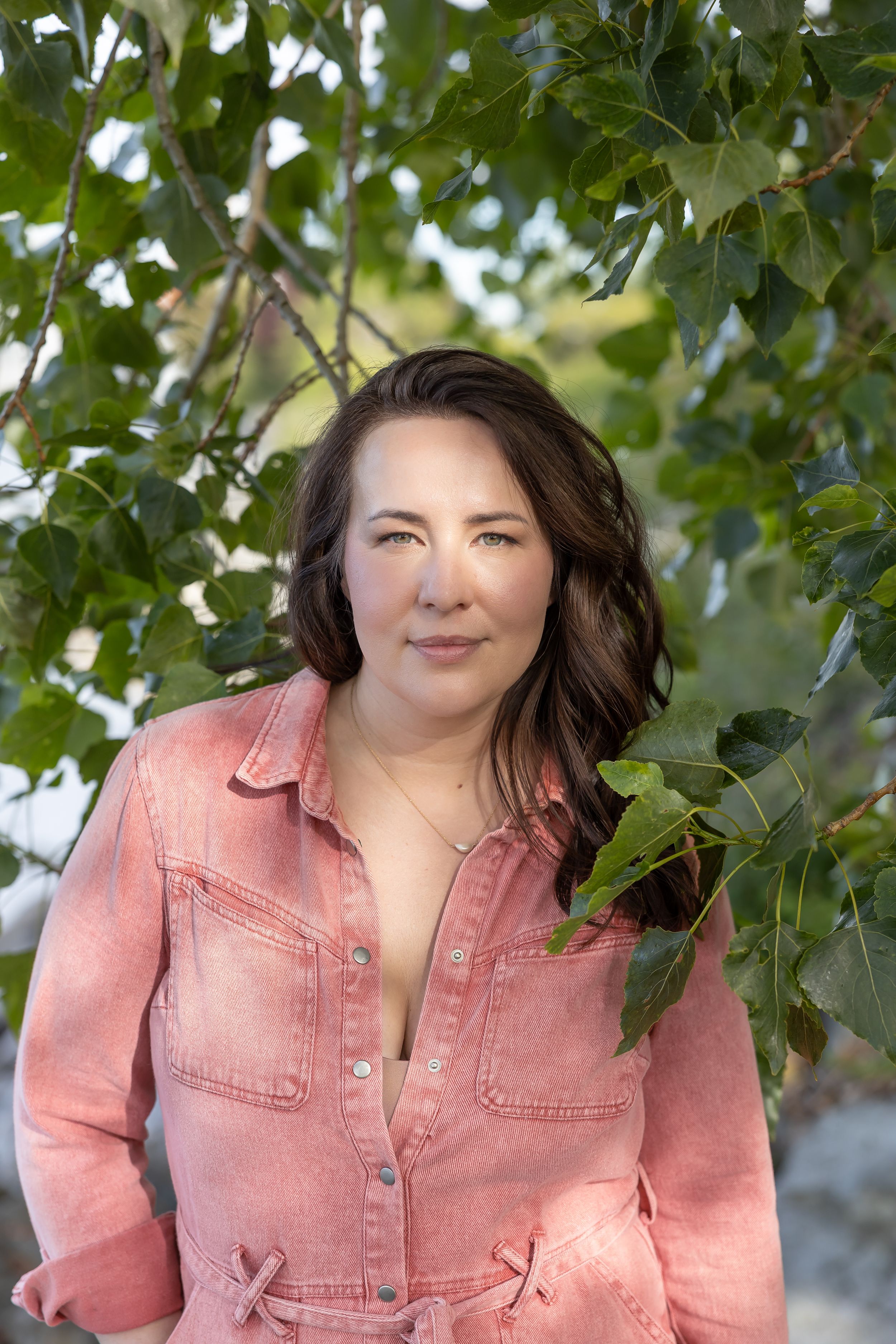 Woman business owner Talks Over Tea Mental Health Therapist in Tacoma, WA personal branding dapple lighting in trees wearing pink jumpsuit
