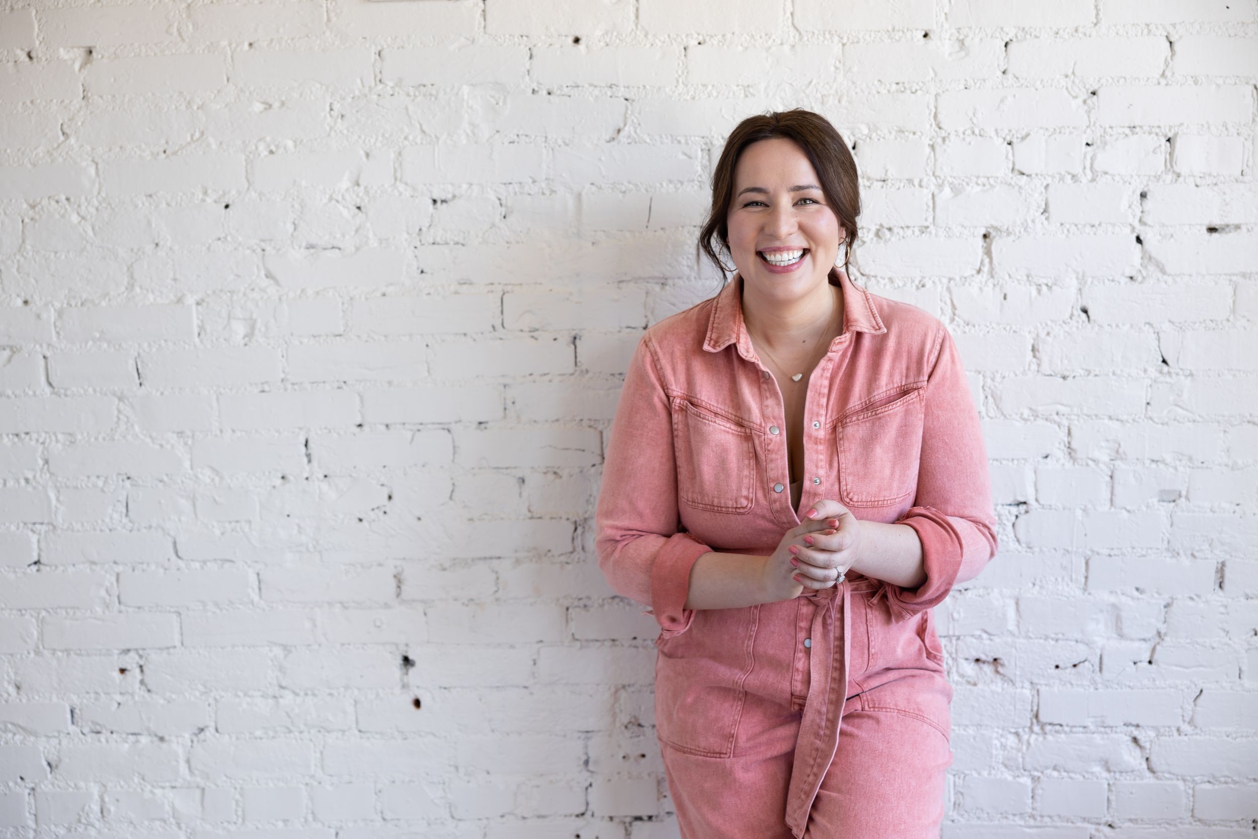 Woman business owner Talks Over Tea Mental Health Therapist in Tacoma, WA personal branding  leaning again white brick studio wall laughing