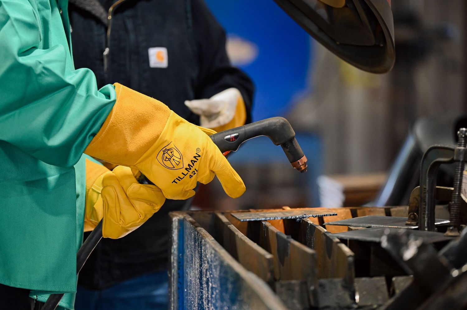 Close-up of hands wearing protective gloves working with industrial machinery and tools.