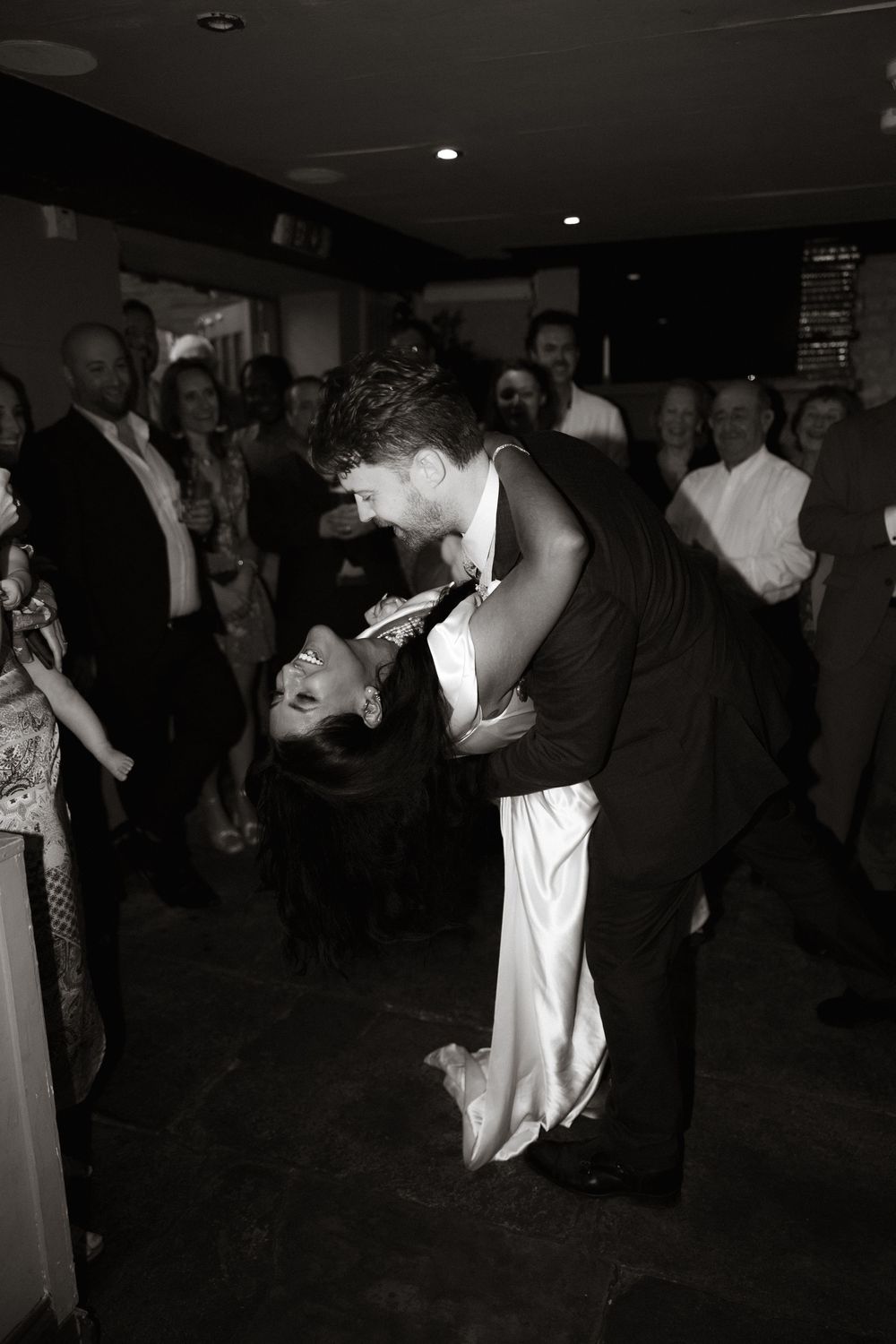 A romantic moment between couples dancing together in a dimly lit venue during a celebration or party.